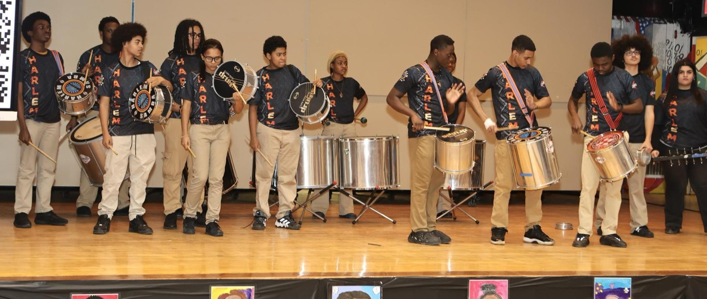 A diverse group of musicians playing drums on stage at a performance